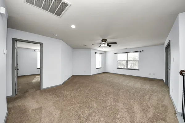 an empty room with windows and ceiling fan