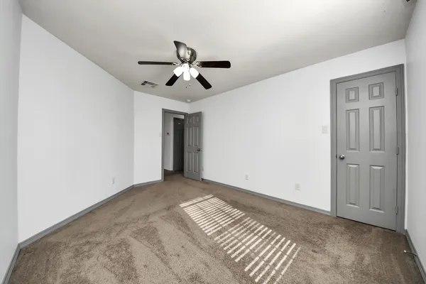 a view of empty room with wooden floor and ceiling fan