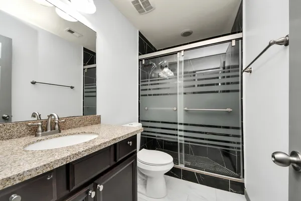 a bathroom with a granite countertop sink toilet and shower