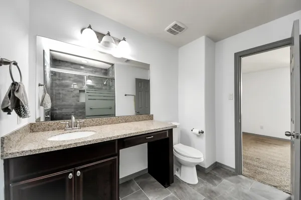 a bathroom with a granite countertop sink a toilet and a mirror