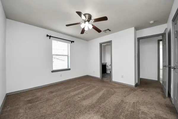 an empty room with ceiling fan and window