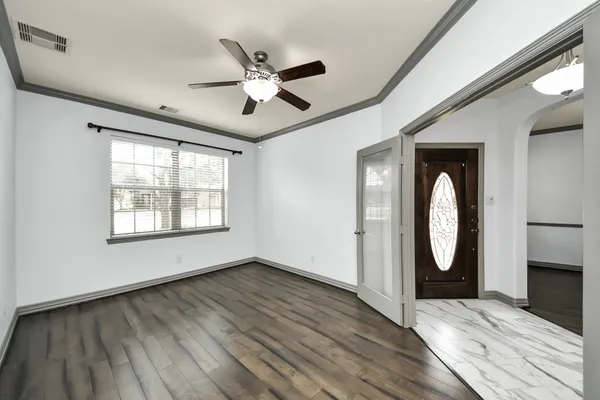 a view of an empty room with wooden floor and a window