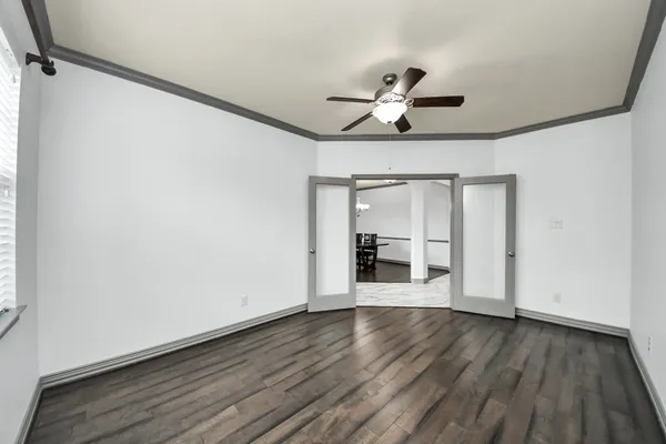 a view of an empty room with wooden floor and a window