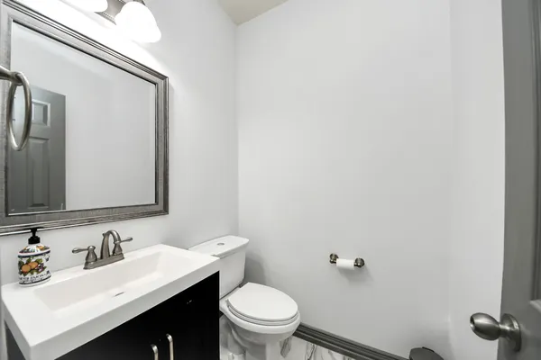 a bathroom with a toilet sink vanity and mirror
