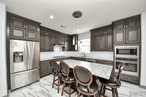 a kitchen with granite countertop a refrigerator stove microwave and cabinets