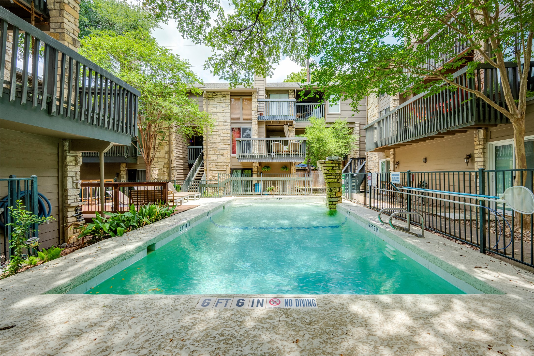 3627 Menchaca Road, Unit 214 Austin, TX 78704 - Photo 25 of 28 A refreshing pool awaits, nestled amidst multi-story buildings and lush, mature trees.