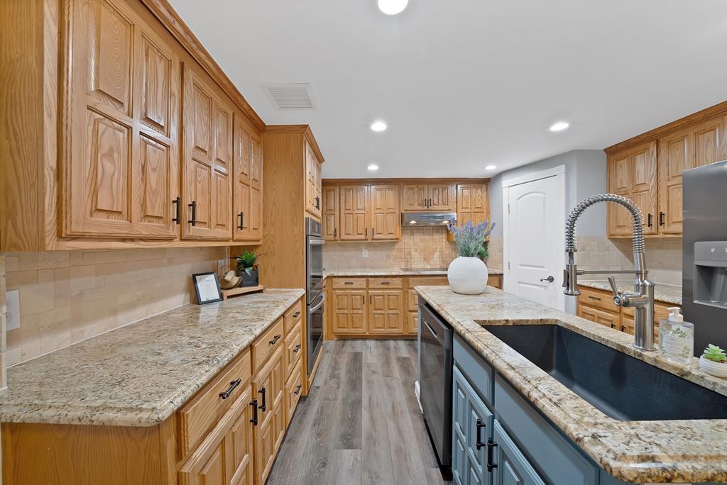 306 Rochelle Boulevard Irving, TX 75062 - Photo 11 of 40 Kitchen featuring wood cabinetry, stone-finish countertops, wood-finish flooring, recessed lighting, and a large central island
