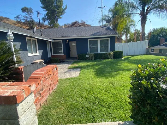 a backyard of a house with table and chairs plants and large tree