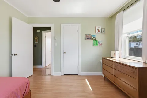 a view of a bedroom with wooden floor and windows
