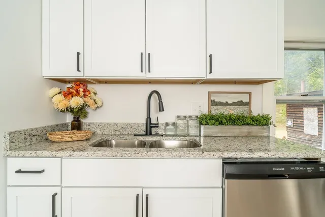 a kitchen with granite countertop a sink a stove and cabinets