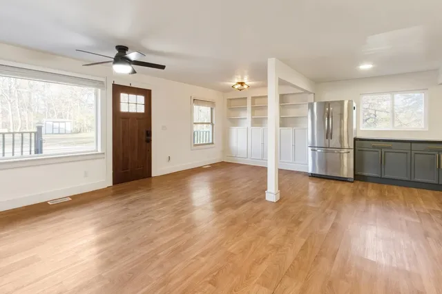 an empty room with wooden floor cabinet and windows