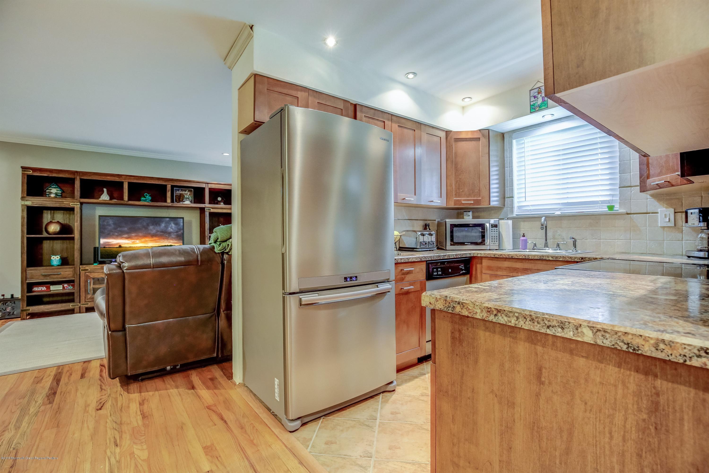 a kitchen with stainless steel appliances granite countertop a refrigerator a stove and a sink with wooden floors