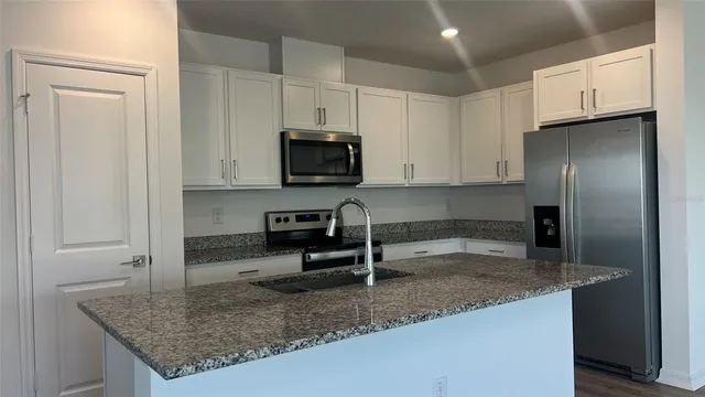 a kitchen with stainless steel appliances granite countertop a sink stove and refrigerator