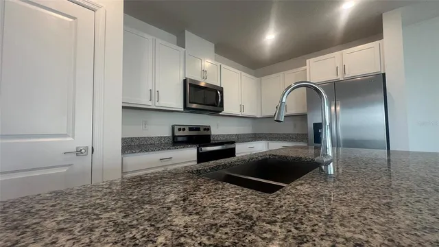 a kitchen with kitchen island granite countertop a stove a sink and a microwave