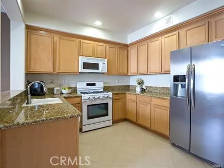 a kitchen with granite countertop a refrigerator stove top oven a sink and dishwasher