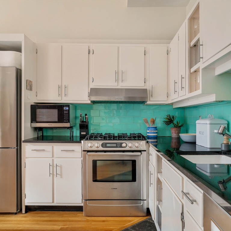 61 Dana Street, Unit 4 Cambridge, MA 02138 - Photo 8 of 25 a kitchen with white cabinets and appliances