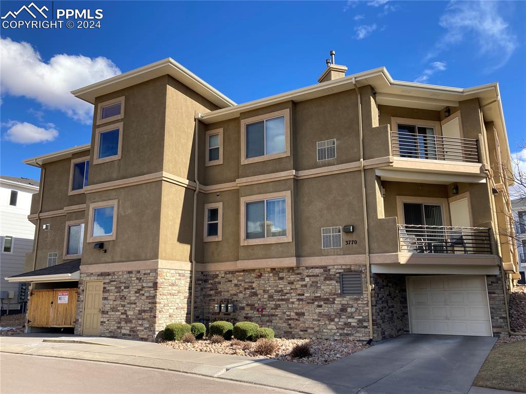 View of condo featuring beautiful stucco & stone exterior.