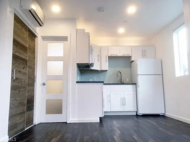 a kitchen with a refrigerator a sink and dishwasher with wooden floor