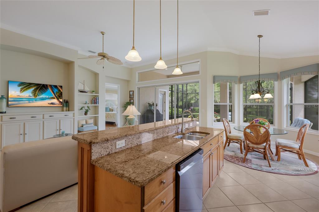 11709 Strandhill Court Lakewood Ranch, FL 34202 - Photo 18 of 51 a kitchen with granite countertop a stove a sink a dining table and chairs with wooden floor