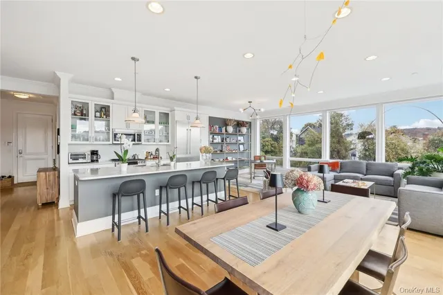 a living room with stainless steel appliances furniture a rug kitchen view and a large window