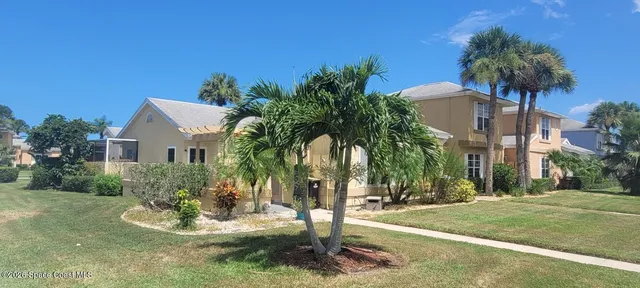 a palm tree sitting in front of a house with a yard