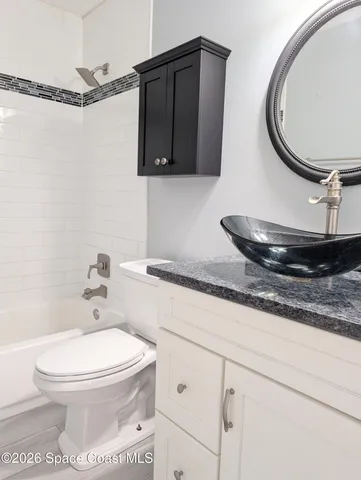 a bathroom with a granite countertop toilet sink and mirror