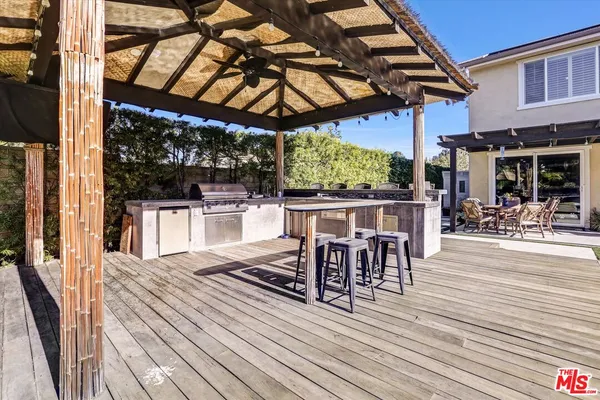 a view of a patio with table and chairs a barbeque with wooden floor and roof with a barbeque grill