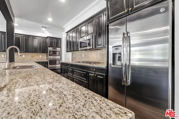 a kitchen with stainless steel appliances kitchen island granite countertop a refrigerator and a sink
