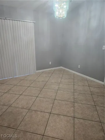 a view of an empty room and chandelier fan