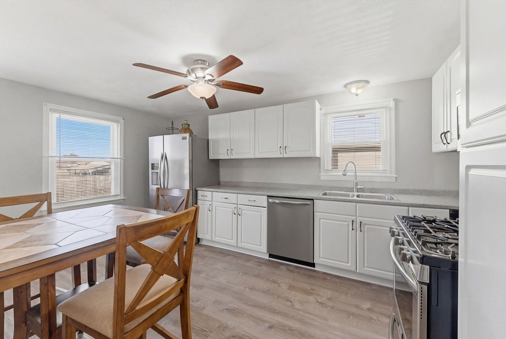 76 Lake Street Pawtucket, RI 02860 - Photo 6 of 18 a kitchen with stainless steel appliances granite countertop a stove a sink dishwasher a refrigerator with white cabinets and wooden floor