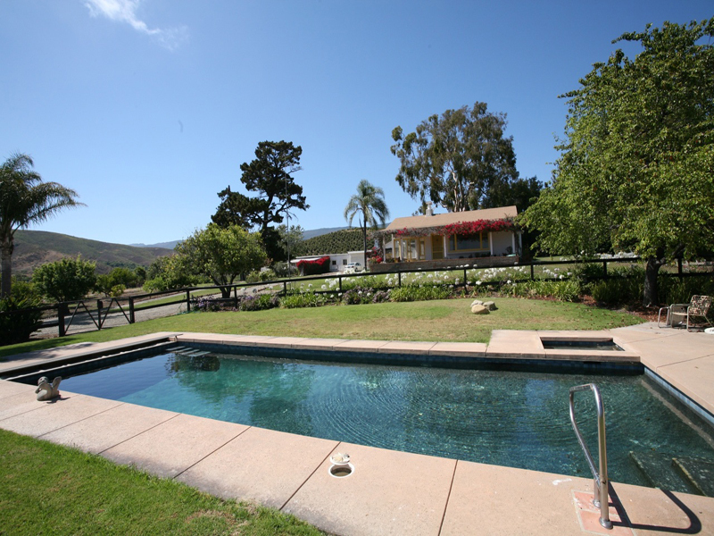 a view of swimming pool with seating area and trees in the background
