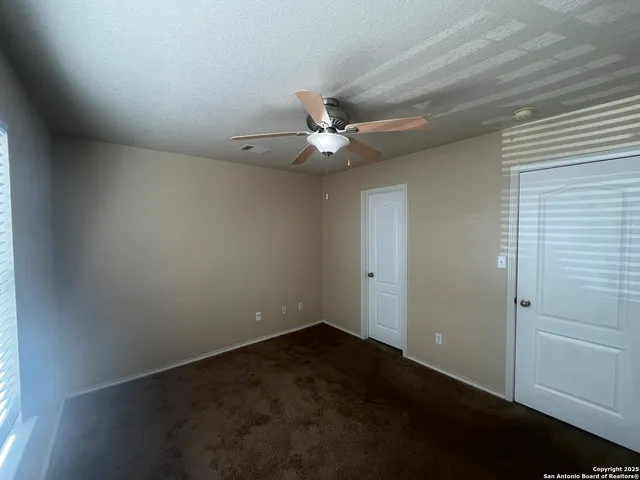 an empty room with a ceiling fan and window