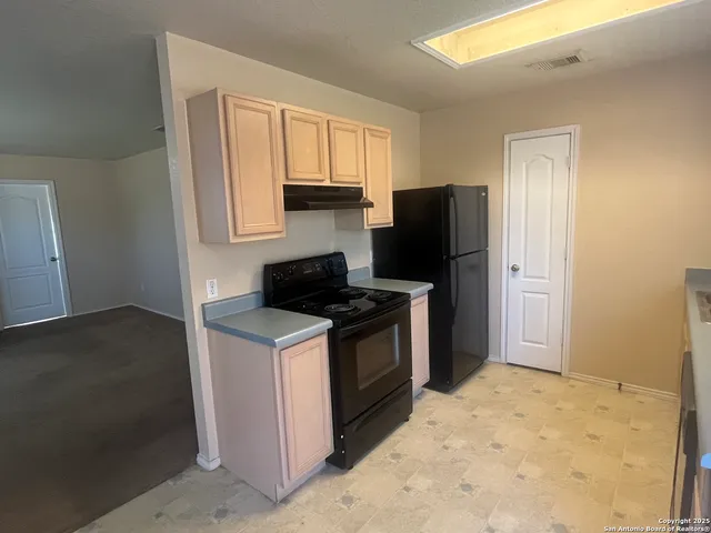 a kitchen with a stove top oven and refrigerator