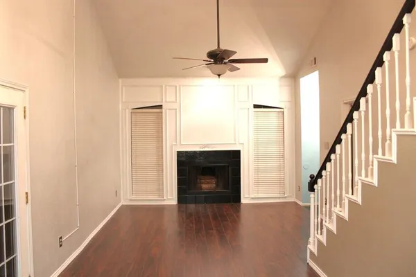 a view of a livingroom with wooden floor fireplace and a ceiling fan