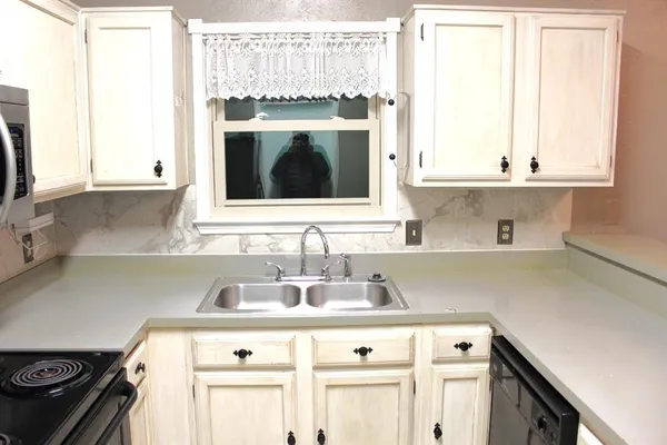 a kitchen with granite countertop a sink stove and cabinets