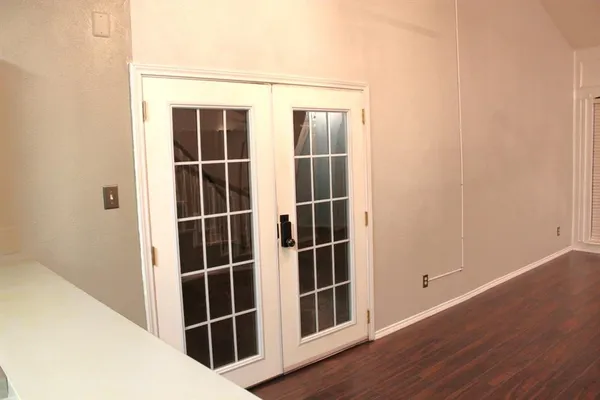 a view of an empty room with wooden floor and windows