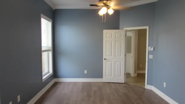 an empty room with windows and chandelier fan