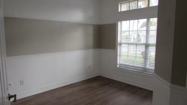 an empty room with wooden floor and windows