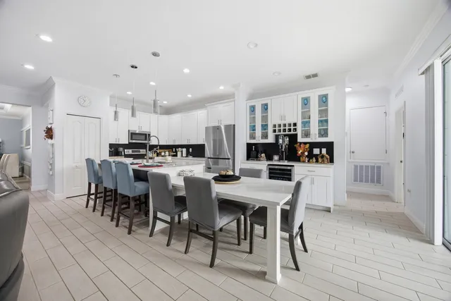 a kitchen with stainless steel appliances kitchen island granite countertop a dining table chairs and stove top oven with wooden floor