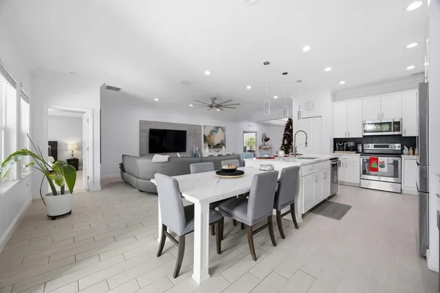 a living room with stainless steel appliances furniture a flat screen tv and a window