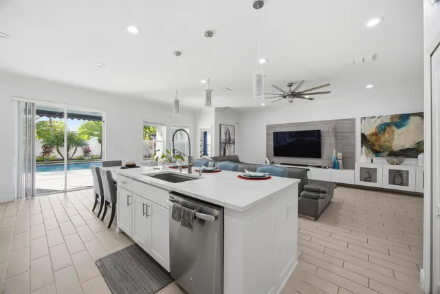 a large white kitchen with a large island in the center and living room