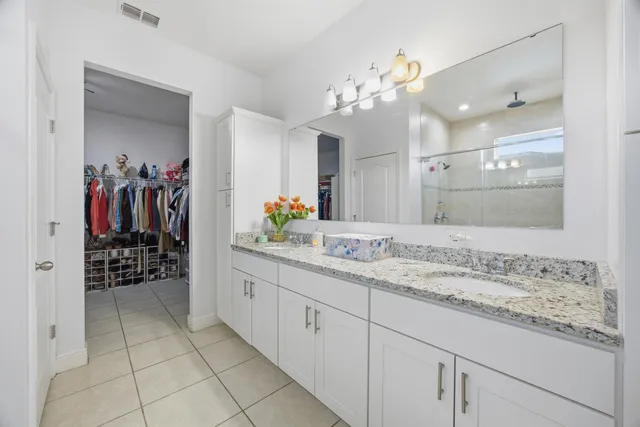 a bathroom with a granite countertop sink a mirror and a shower
