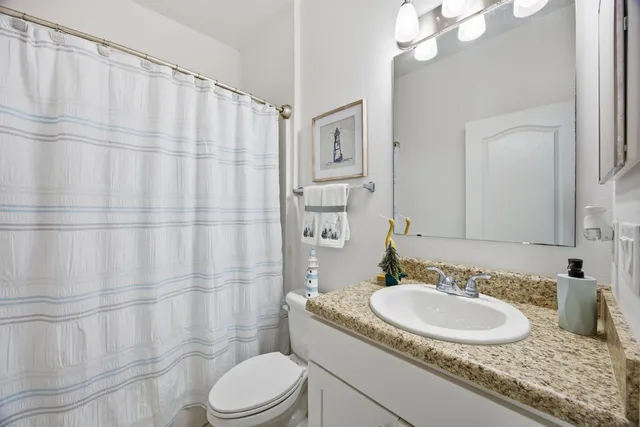 a bathroom with a granite countertop sink a toilet and a mirror