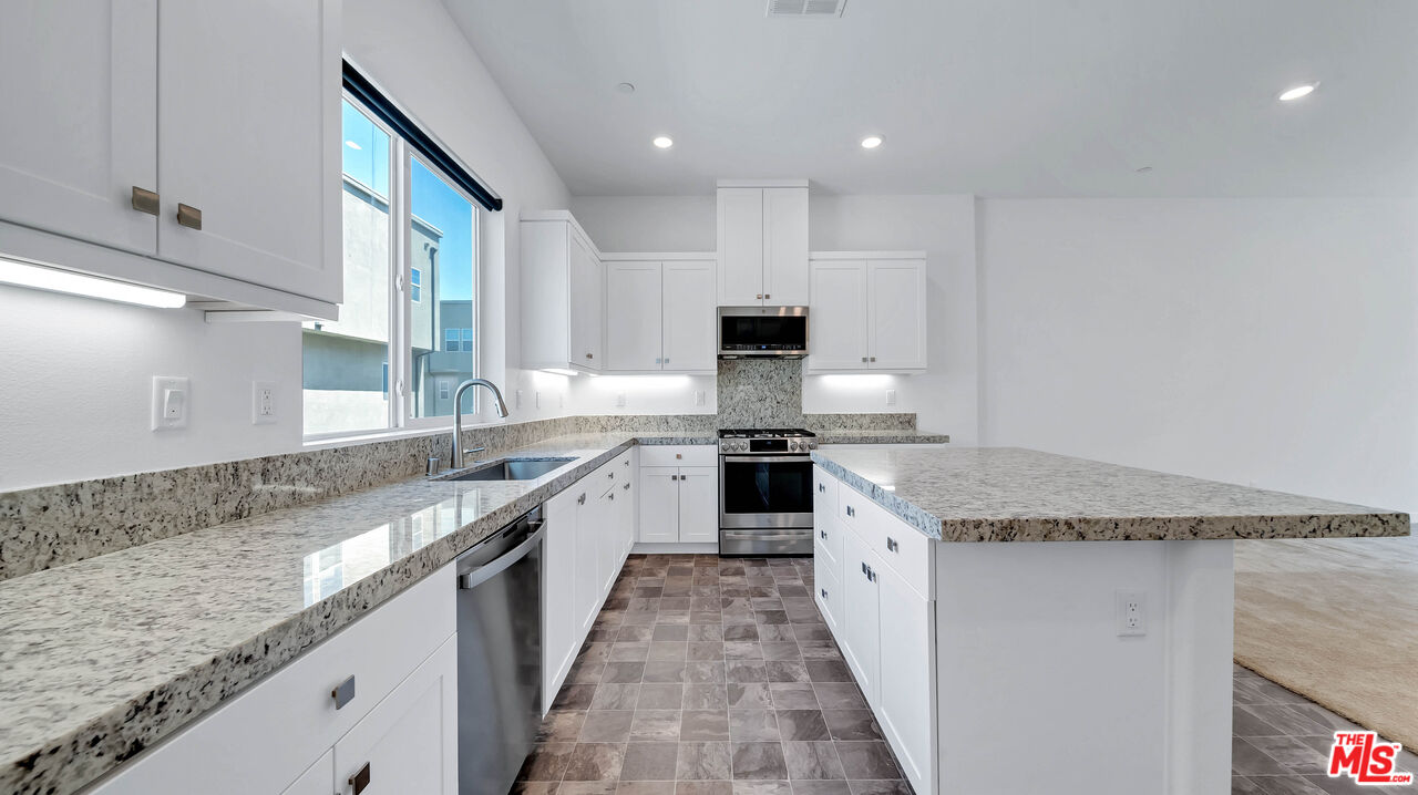 27009 Hummingbird Lane Valencia, CA 91381 - Photo 16 of 35 a large kitchen with granite countertop a sink and dishwasher a stove top oven with wooden floor