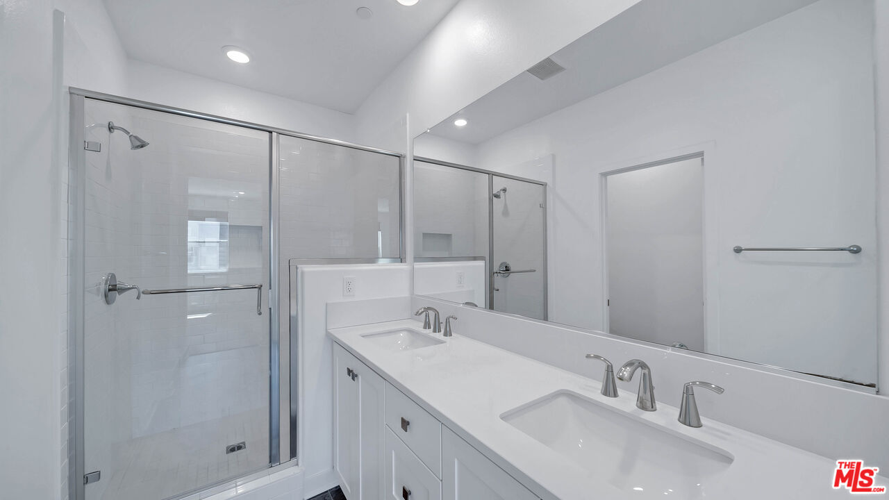 27009 Hummingbird Lane Valencia, CA 91381 - Photo 31 of 35 a bathroom with a shower sink vanity and mirror