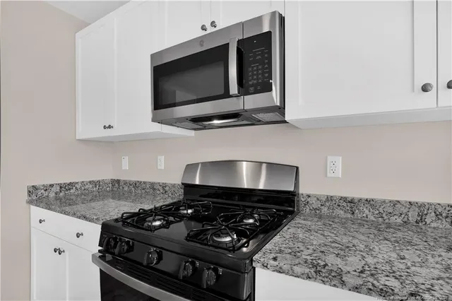 a kitchen with stainless steel appliances granite countertop white cabinets and black stove top oven with granite countertops