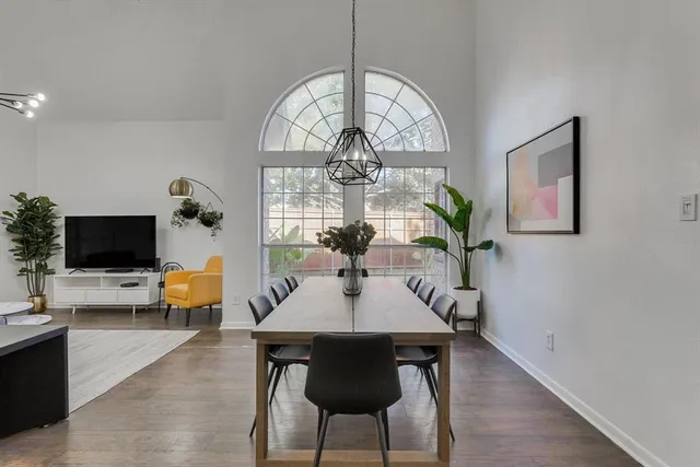 a dining room with wooden floor a chandelier a wooden table and chairs