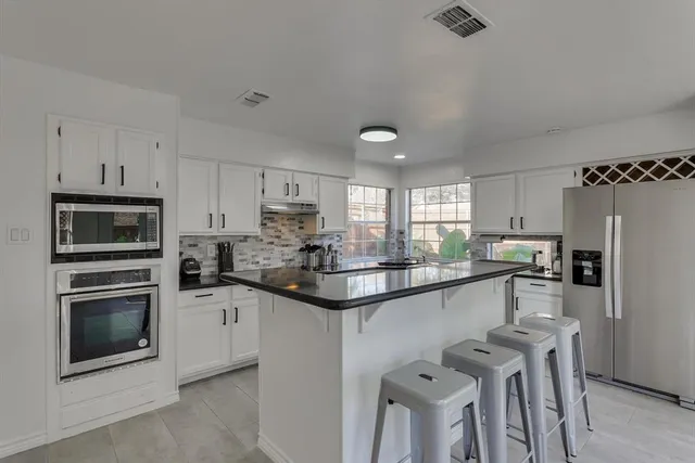 a kitchen with granite countertop kitchen island white cabinets and stainless steel appliances