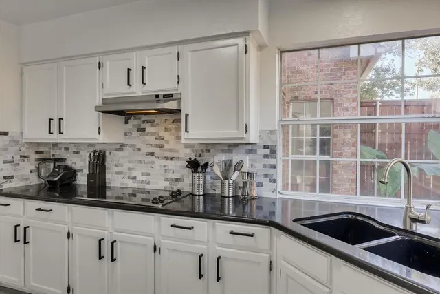 a kitchen with white cabinets a sink and a window