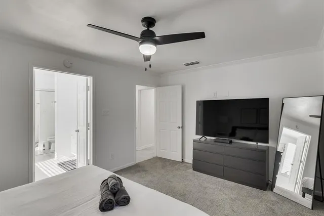a living room with flat screen tv and a ceiling fan